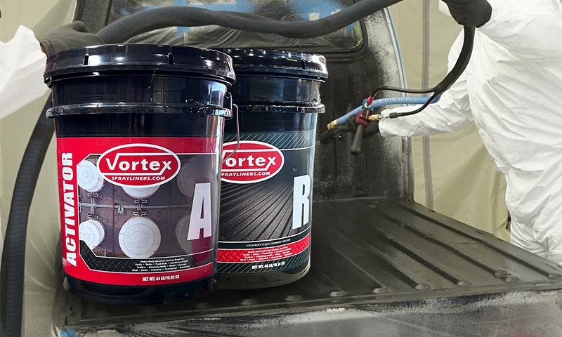 Person spraying truck bed liner with two 5 gallon pails with polyurea material